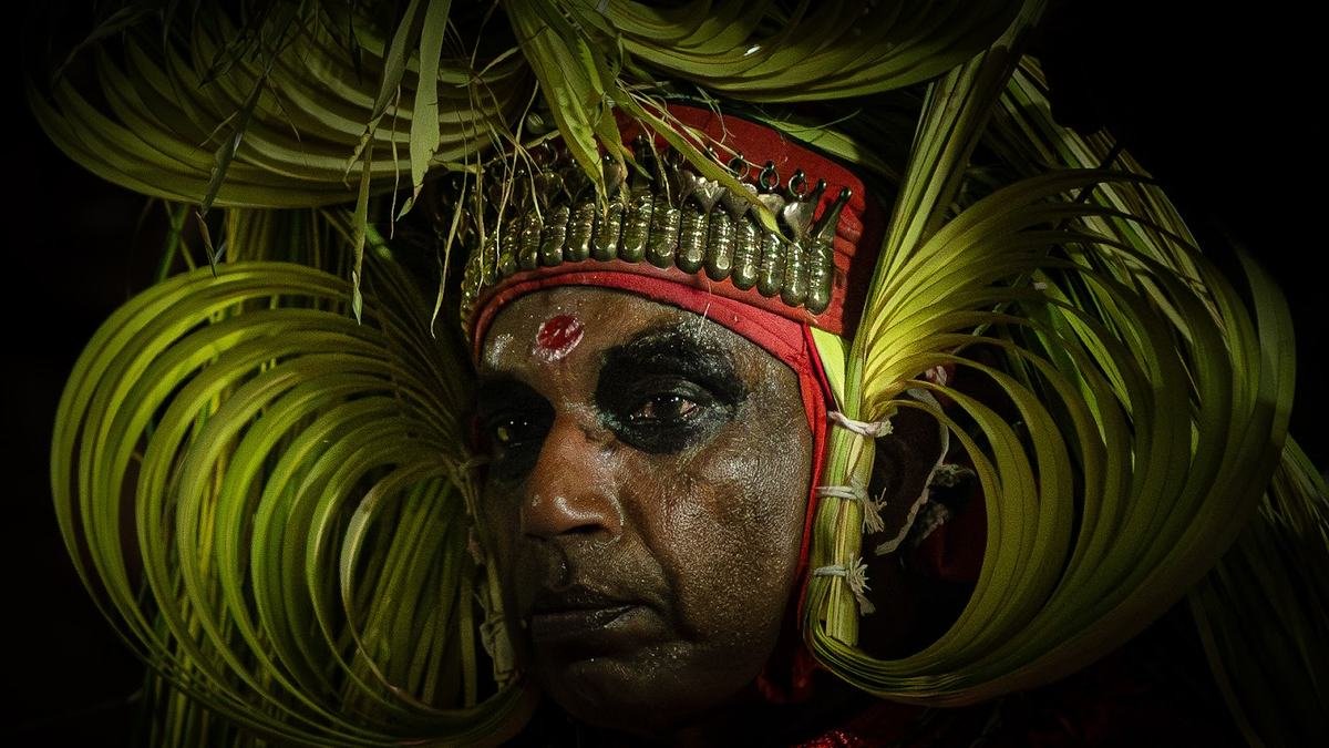 Close view of a Theyyam with a green palm-frond headdress
