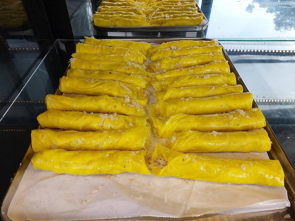 Rows of rolled yellow Elanchi pancakes on a tray