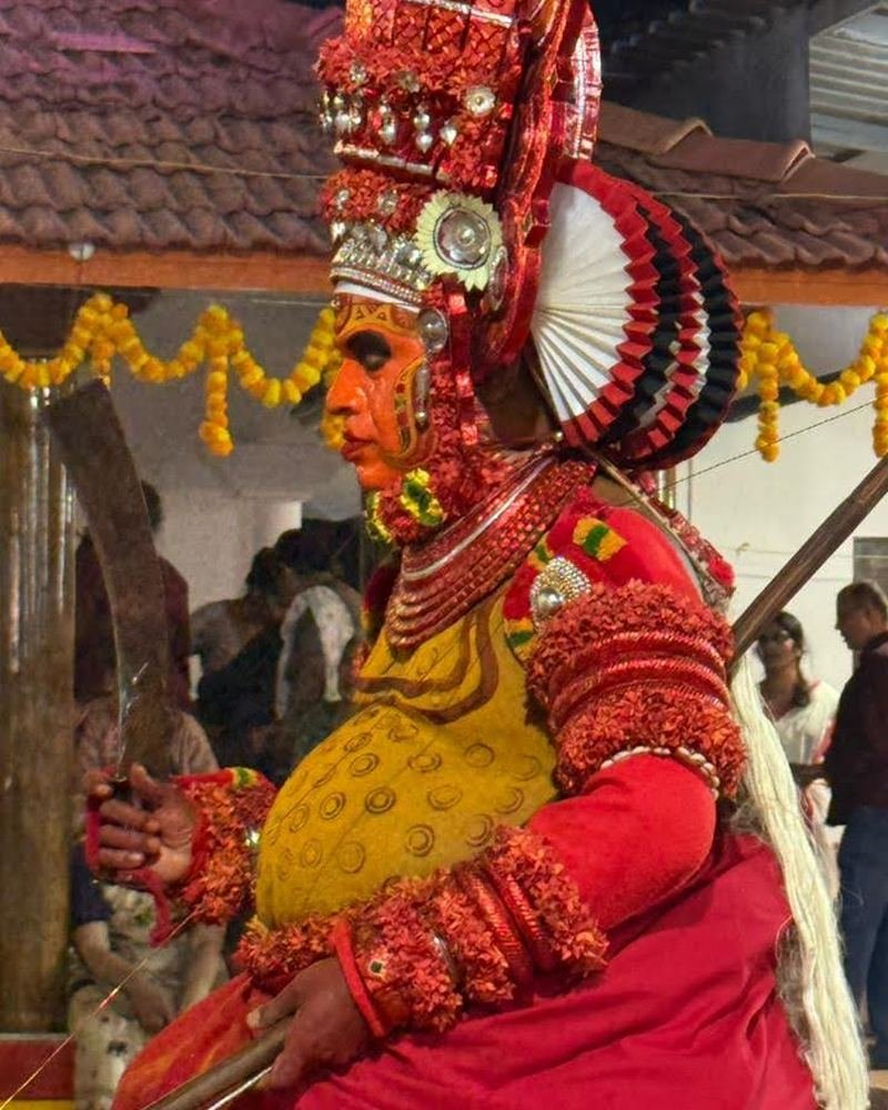 Profile of a Theyyam in a red and gold headdress