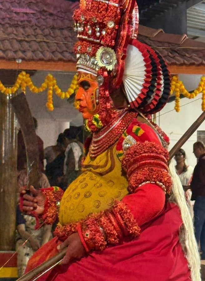 Profile of a Theyyam in a red and gold headdress