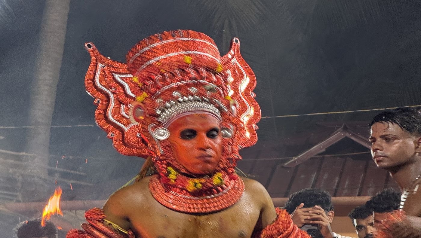 Portrait of a Theyyam in a red headdress during the ritual