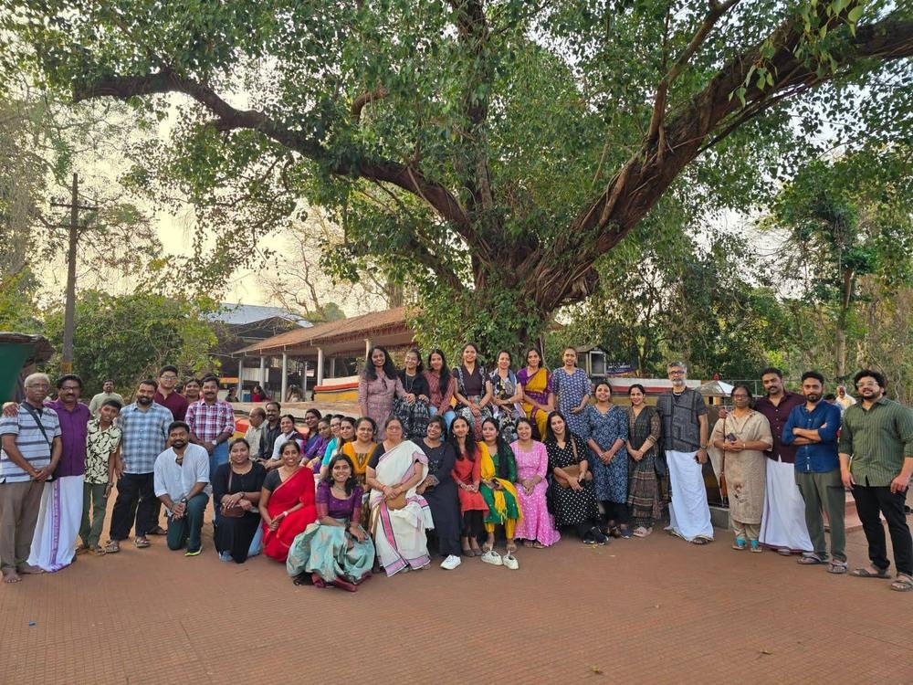 Guests of the Theyyam trip standing together under a large banyan tree