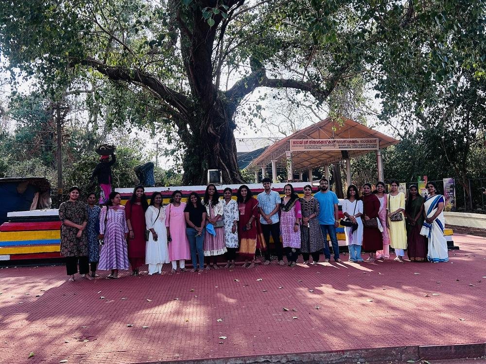 Guests of the Theyyam trip standing together under a banyan tree near a shrine
