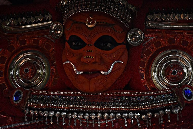 Neeliyar Bhagavathi Theyyam in a red face mask with silver discs and ornaments, at Neeliyar Kottam