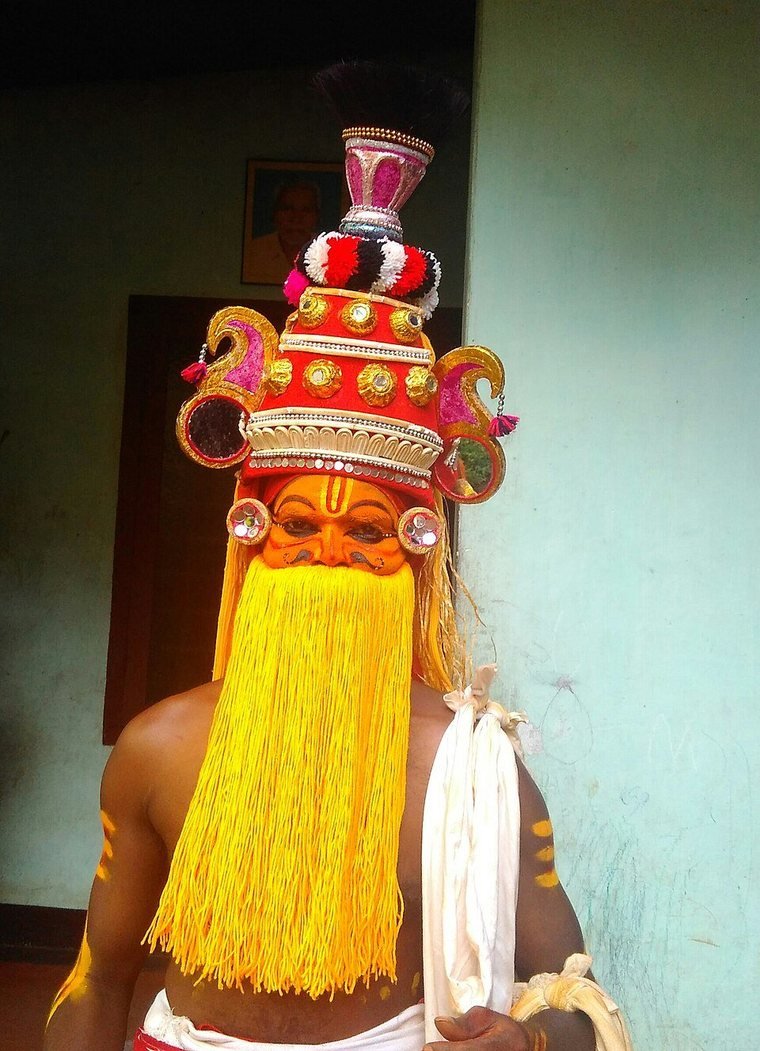 Onapottan with a long yellow beard of fibre, a tall crown and red face paint