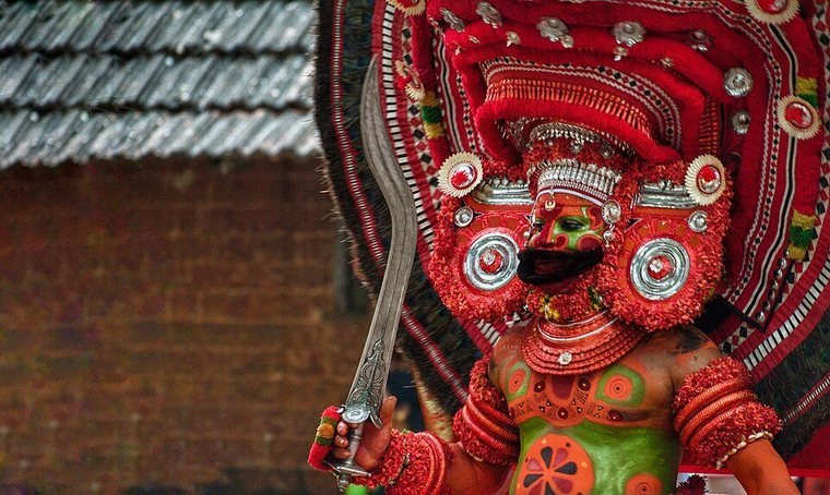 Vettakkorumakan Theyyam in a red crown and ornaments, holding a sword